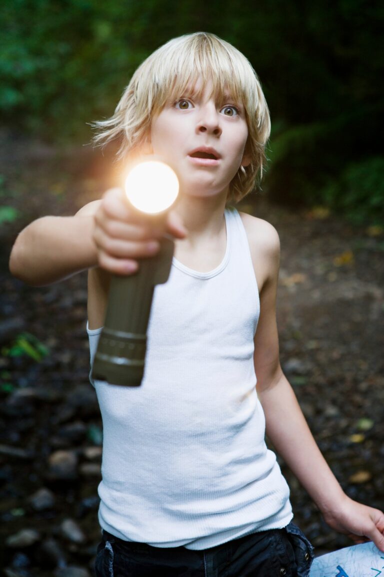 Young explorer with flashlight in the woods