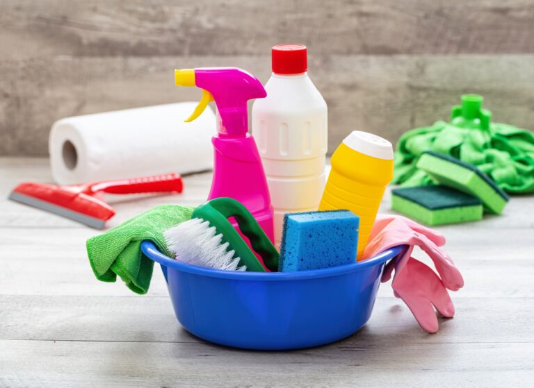 Cleaning supplies in a blue bowl, wooden floor background.